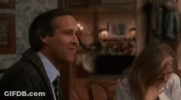 A Man And A Woman Are Sitting In A Room With A Fire Coming Out Of A Fireplace . GIF