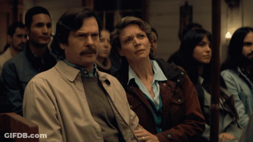 A Man And A Woman Are Sitting In A Row Of People GIF