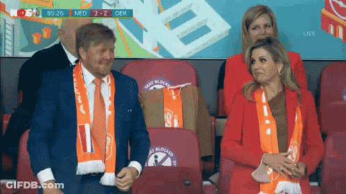 A Man And A Woman Are Sitting In A Stadium Watching A Game . GIF