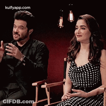A Man And A Woman Are Sitting In Chairs And Smiling . GIF