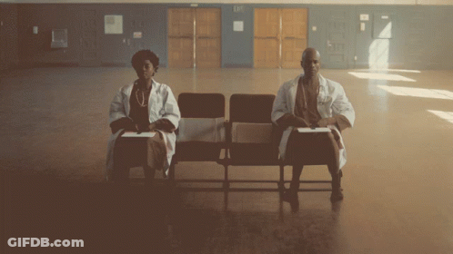 A Man And A Woman Are Sitting In Chairs Holding Signs That Say 9.4 GIF