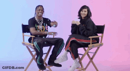 A Man And A Woman Are Sitting In Directors Chairs And Smiling GIF