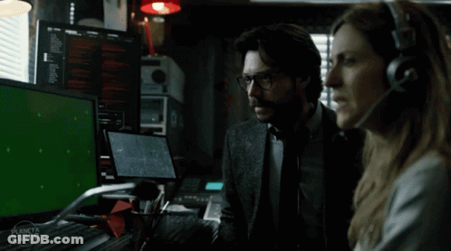 A Man And A Woman Are Sitting In Front Of A Green Screen GIF