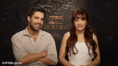 A Man And A Woman Are Sitting In Front Of A Poster For Max Hbo Original House Of The Dragon GIF