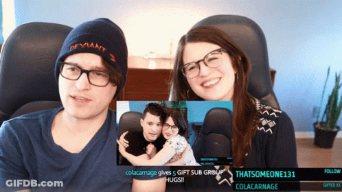 A Man And A Woman Are Sitting In Front Of A Screen That Says Colacarnage GIF
