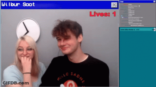 A Man And A Woman Are Sitting In Front Of A Screen That Says Wilbur Soot Lives 1 GIF