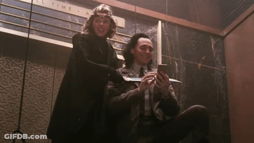 A Man And A Woman Are Sitting In Front Of A Sign That Says " All Time " GIF