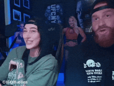A Man And A Woman Are Sitting In Front Of A Sign That Says UFC Ny GIF