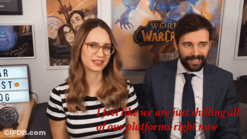 A Man And A Woman Are Sitting In Front Of A Sign That Says World Of Warcraft GIF
