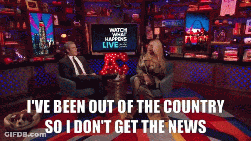 A Man And A Woman Are Sitting In Front Of A Tv That Says Watch What Happens Live GIF