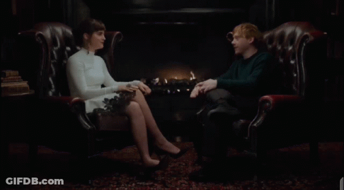 A Man And A Woman Are Sitting In Leather Chairs Laughing GIF