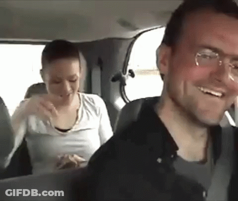 A Man And A Woman Are Sitting In The Back Of A Car . GIF