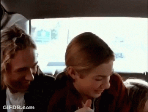 A Man And A Woman Are Sitting In The Back Of A Car . GIF