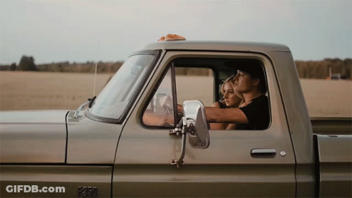 A Man And A Woman Are Sitting In The Back Of A Pickup Truck With The Number 1250 On The Side GIF