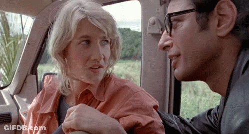 A Man And A Woman Are Sitting In The Back Seat Of A Car . GIF