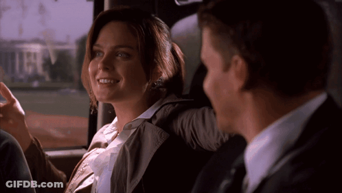 A Man And A Woman Are Sitting In The Back Seat Of A Car And The Woman Is Smiling GIF