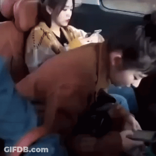 A Man And A Woman Are Sitting In The Back Seat Of A Car . GIF