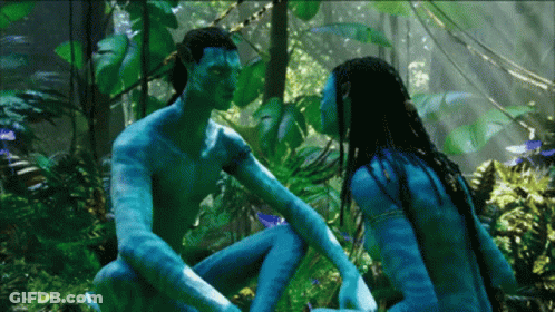 A Man And A Woman Are Sitting In The Jungle And Looking At Each Other GIF