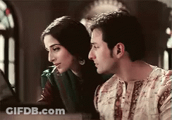 A Man And A Woman Are Sitting Next To Each Other And Looking At Something . GIF