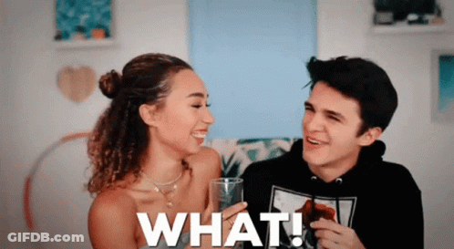 A Man And A Woman Are Sitting Next To Each Other And The Woman Is Holding A Glass That Says What ! GIF