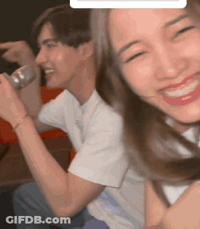A Man And A Woman Are Sitting Next To Each Other And The Woman Is Smiling GIF