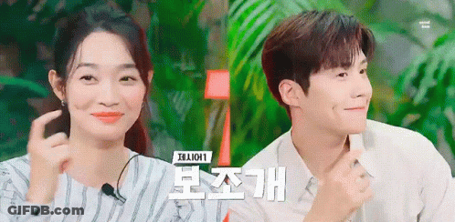 A Man And A Woman Are Sitting Next To Each Other And The Woman Is Smiling . GIF