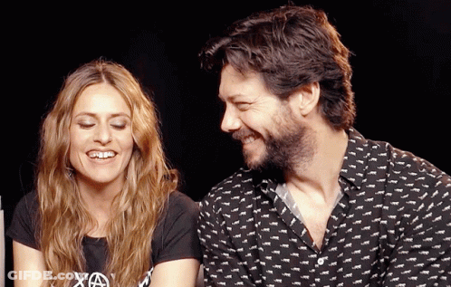 A Man And A Woman Are Sitting Next To Each Other And The Woman Is Wearing A Shirt That Says Xa GIF