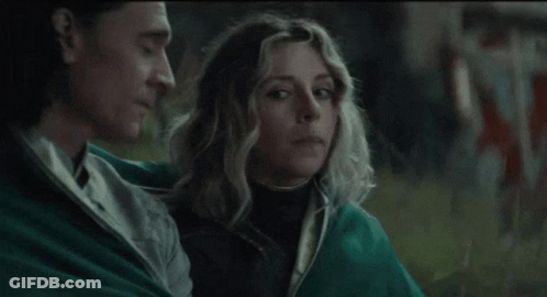 A Man And A Woman Are Sitting Next To Each Other In A Field . GIF