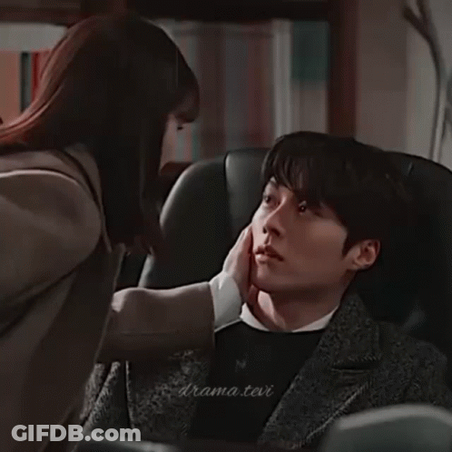 A Man And A Woman Are Sitting Next To Each Other In A Room And Looking At Each Other . GIF
