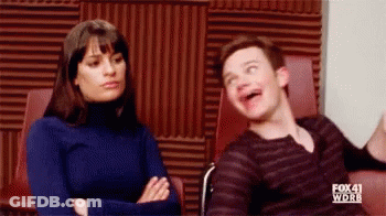 A Man And A Woman Are Sitting Next To Each Other In A Room . The Man Is Making A Funny Face . GIF