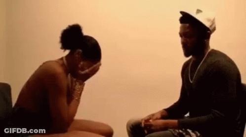 A Man And A Woman Are Sitting Next To Each Other In A Room . The Woman Is Covering Her Face With Her Hands . GIF