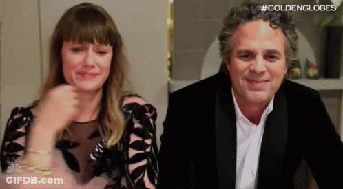 A Man And A Woman Are Sitting Next To Each Other In A Room . The Woman Is Crying And The Man Is Smiling . GIF