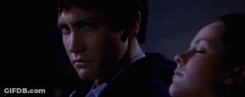 A Man And A Woman Are Sitting Next To Each Other In The Dark . GIF