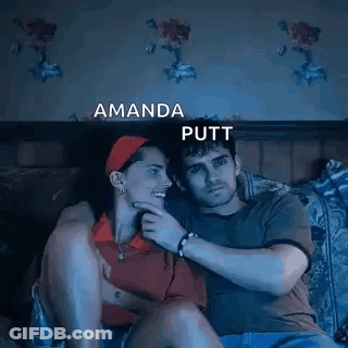 A Man And A Woman Are Sitting Next To Each Other On A Bed Watching A Movie . GIF