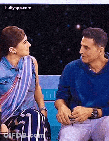 A Man And A Woman Are Sitting Next To Each Other On A Bench . GIF