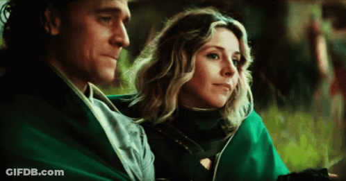 A Man And A Woman Are Sitting Next To Each Other On A Blanket . GIF