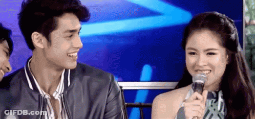 A Man And A Woman Are Sitting Next To Each Other With A Microphone . GIF
