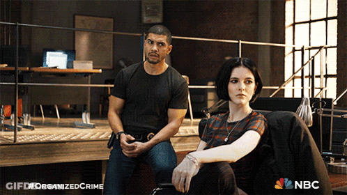 A Man And A Woman Are Sitting Next To Each Other With A Nbc Logo In The Background GIF