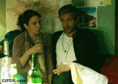 A Man And A Woman Are Sitting Next To Each Other With Bottles Of Alcohol In Front Of Them GIF