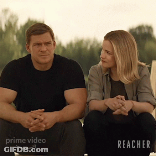 A Man And A Woman Are Sitting Next To Each Other With The Word Reacher On The Bottom Right GIF