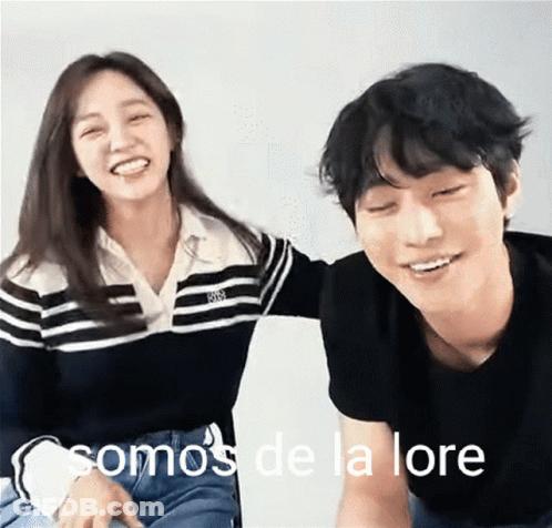 A Man And A Woman Are Sitting Next To Each Other With The Words Somos De La Lore On The Bottom Right GIF