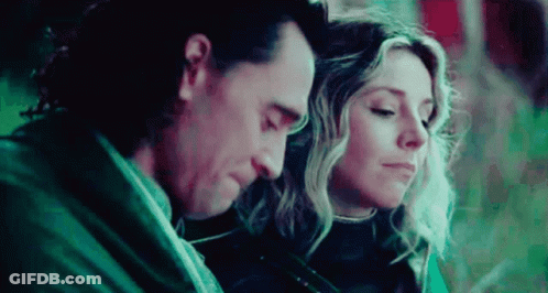 A Man And A Woman Are Sitting Next To Each Other With Their Heads Together . GIF