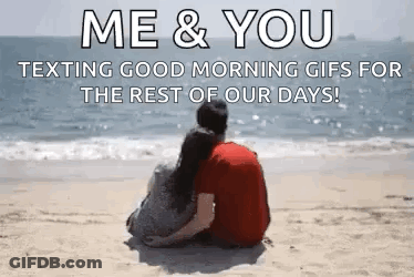 A Man And A Woman Are Sitting On A Beach Looking At The Ocean . GIF