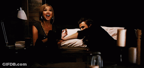 A Man And A Woman Are Sitting On A Bed And The Woman Is Screaming GIF