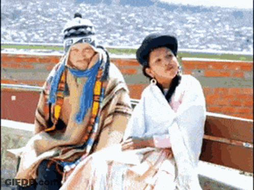 A Man And A Woman Are Sitting On A Bench And The Man Is Wearing A Hat That Says ' A ' On It GIF