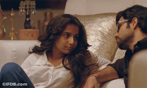 A Man And A Woman Are Sitting On A Couch GIF