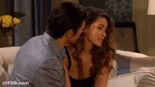 A Man And A Woman Are Sitting On A Couch And Kissing GIF