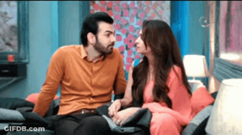 A Man And A Woman Are Sitting On A Couch And Talking To Each Other . GIF