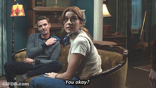A Man And A Woman Are Sitting On A Couch And The Woman Is Asking If They Are Okay GIF