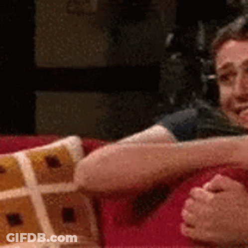 A Man And A Woman Are Sitting On A Couch Holding Hands . GIF